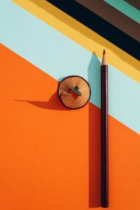 Pencil and shavings from sharpening, on colored striped papers background. Back to school concept